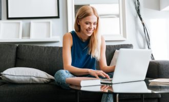 happy woman sitting on sofa using a laptop