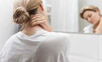 woman looking in mirror having neck pain
